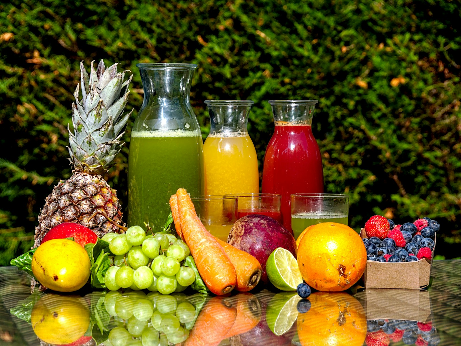Fresh fruit and vegetable juices in glass bottles beside produce, easy fluids that help with hydration and add calories