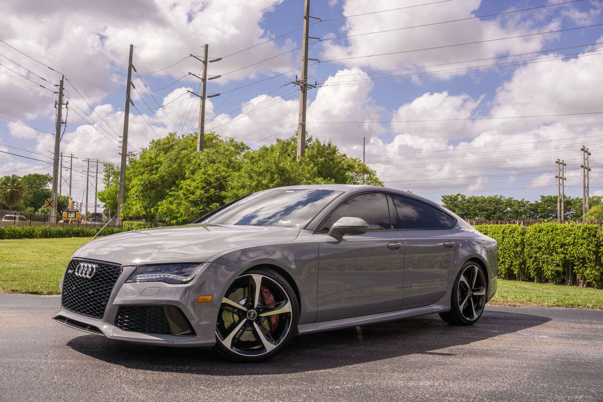 Grey Audi sports car, freshly detailed, parked in a sunny parking lot in southwest florida with grass and a blue sky 