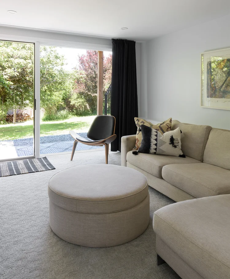 Modern two-story home with large glass windows, warmly lit interiors, and a balcony. Surrounded by trees and a manicured lawn at dusk. Cozy ambiance.