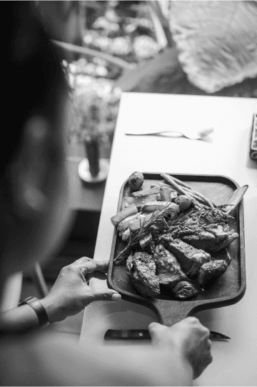 Customer preparing to enjoy a platter of steak and grilled vegetables at a dining table.