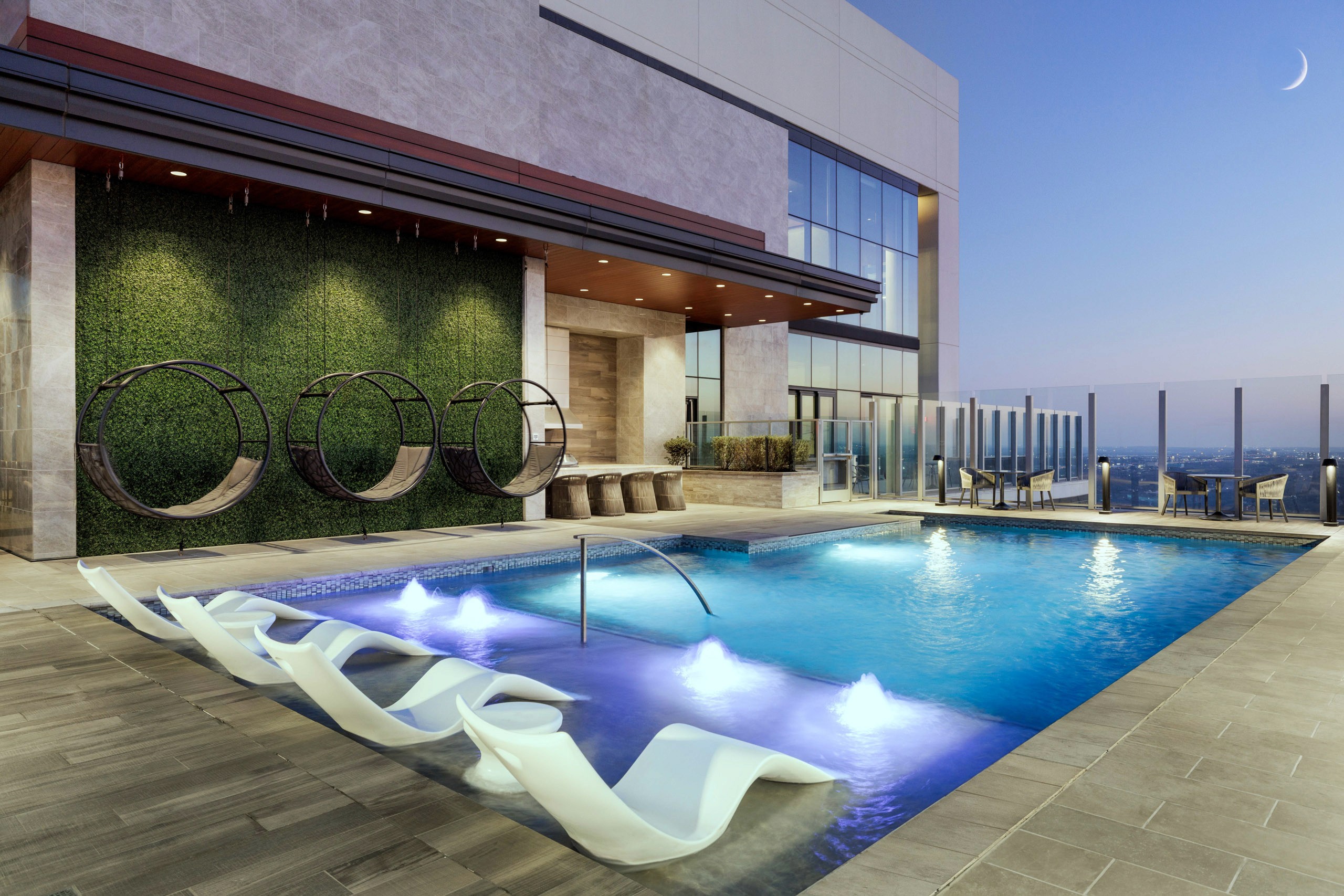 Rooftop pool with modern lounge chairs and hanging seats.