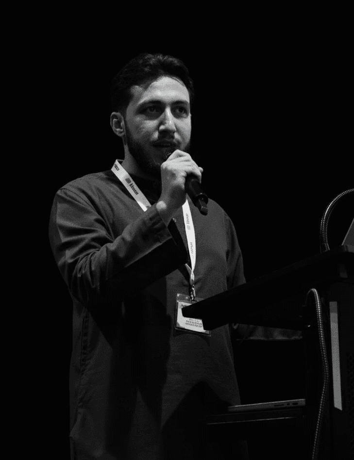 Portrait of a woman with straight long hair, in a dark t-shirt, set against a neutral backdrop.