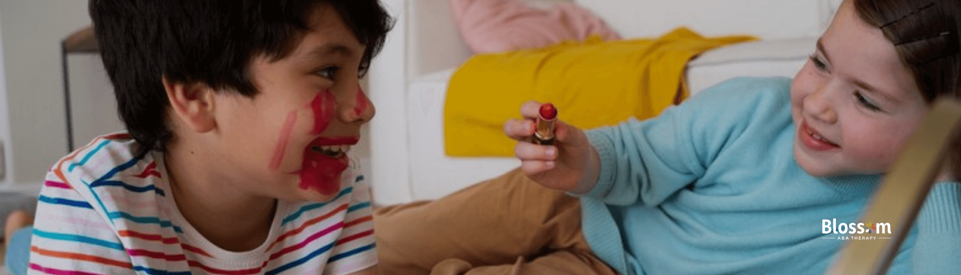 A little boy is letting her sister with mild autism draw on his face using a lipstick