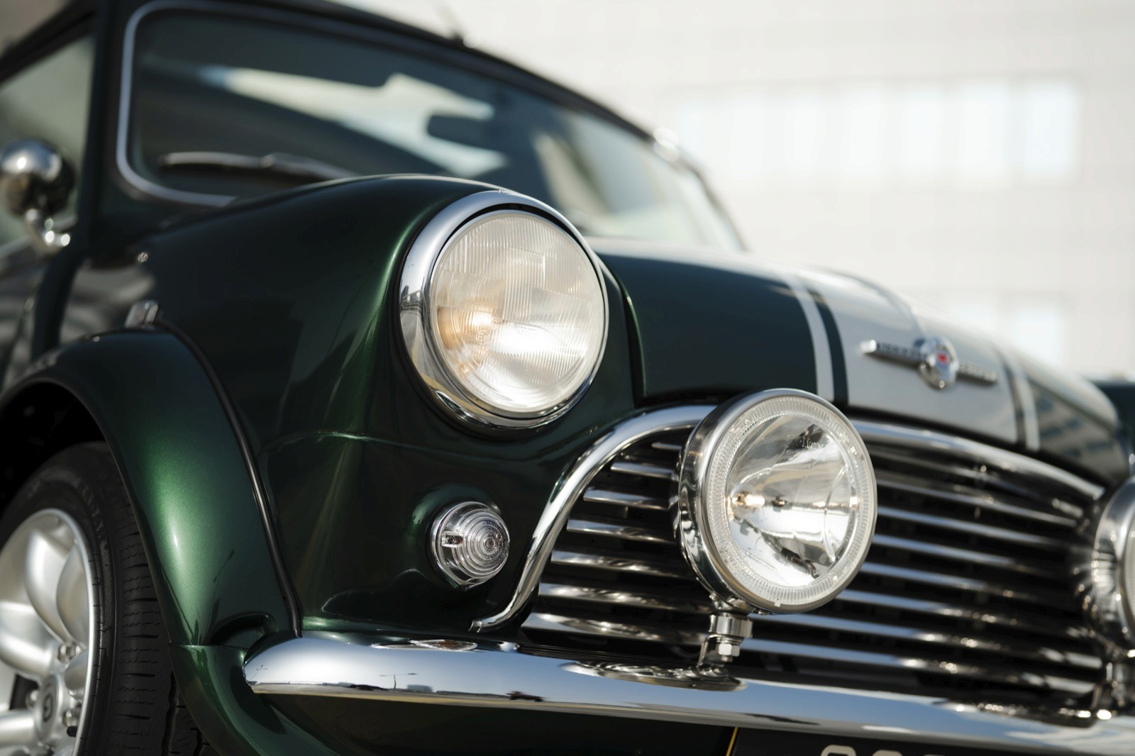 A close-up view of a classic green car's front, showcasing the headlights and grille design.