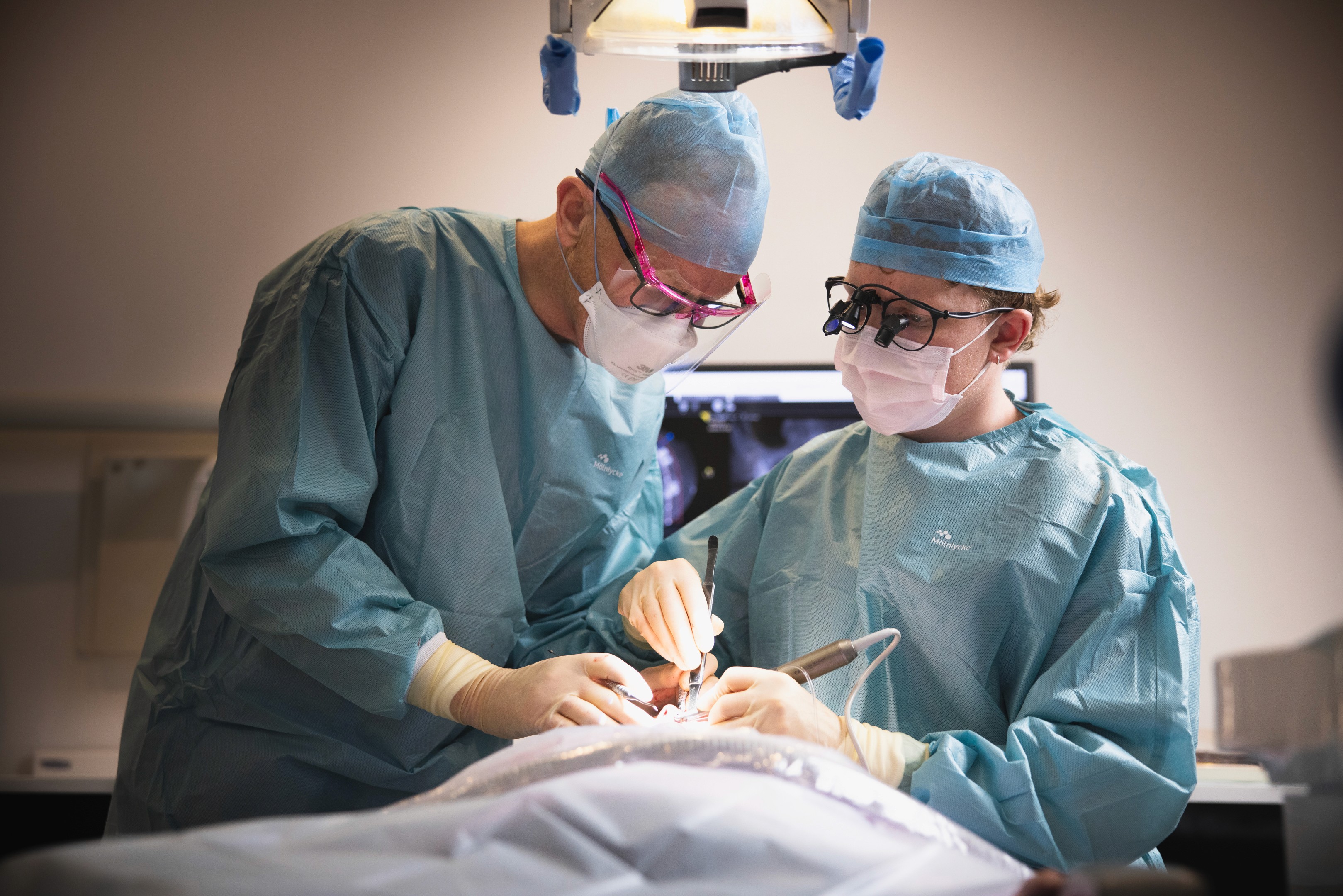 A diverse team collaborates around a table, analyzing documents and charts in a professional setting with a light green background.