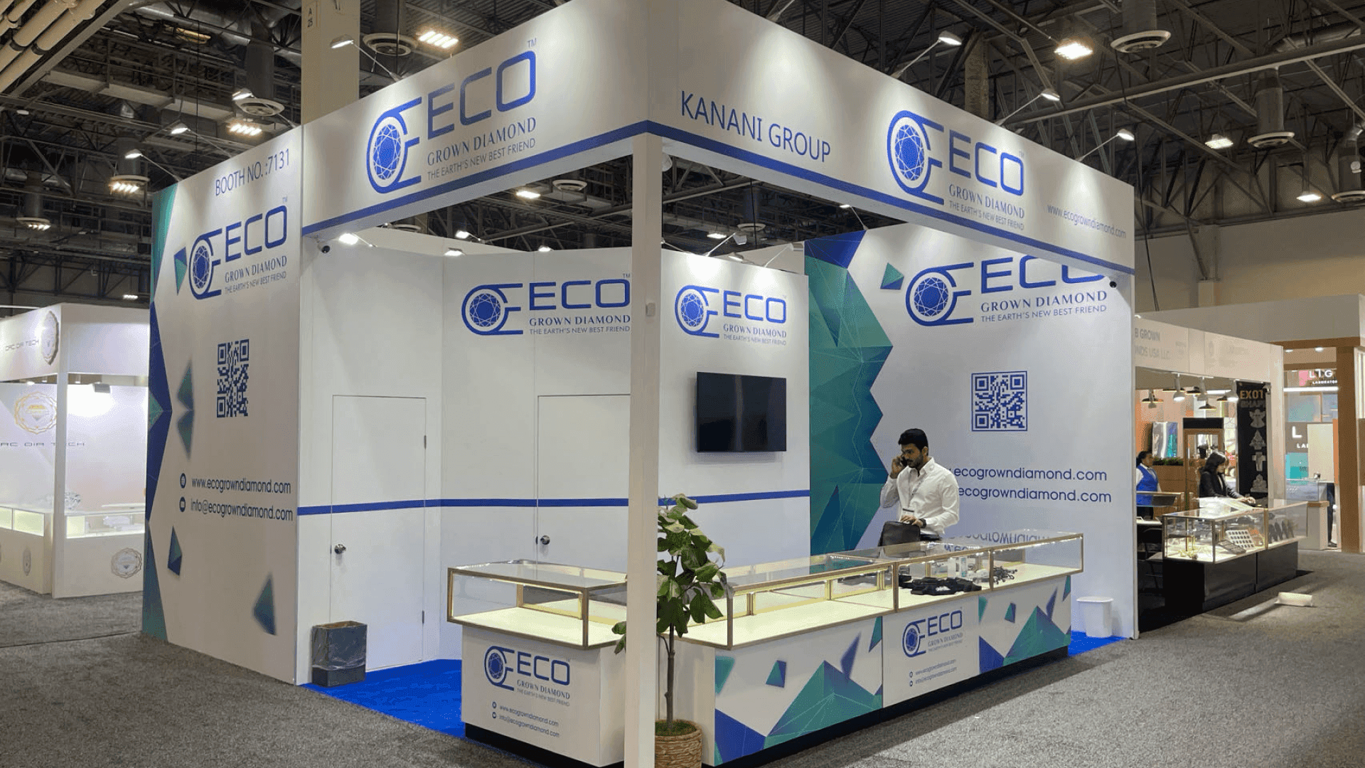 AAA Precious Metals Pawn Expo 2024 booth front-right angle with overhead header, clean wall graphics, and glass product display edge