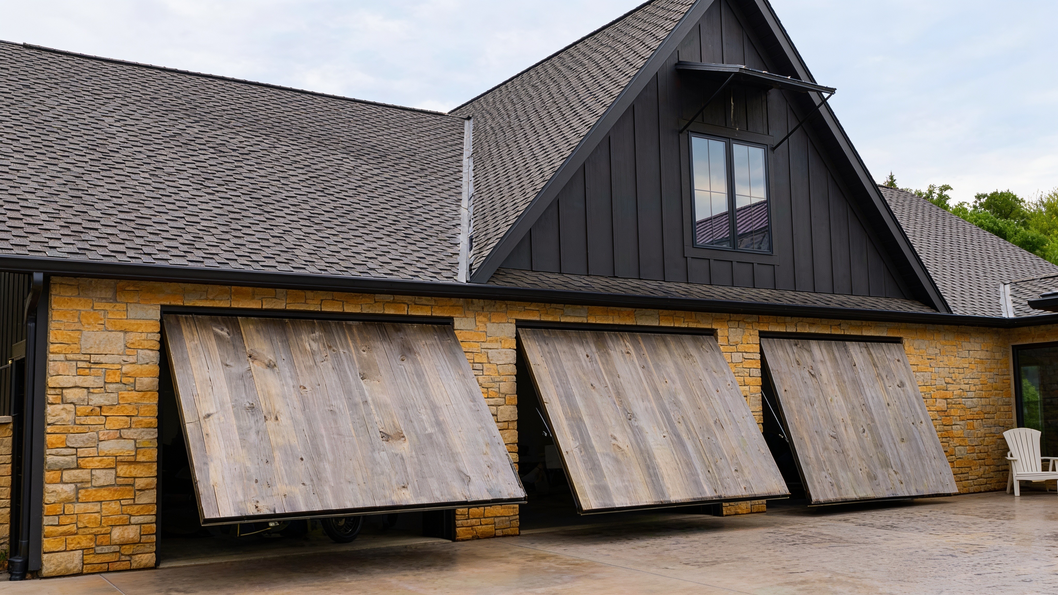 Three concealed cylinder garage doors lifting open on a luxury home