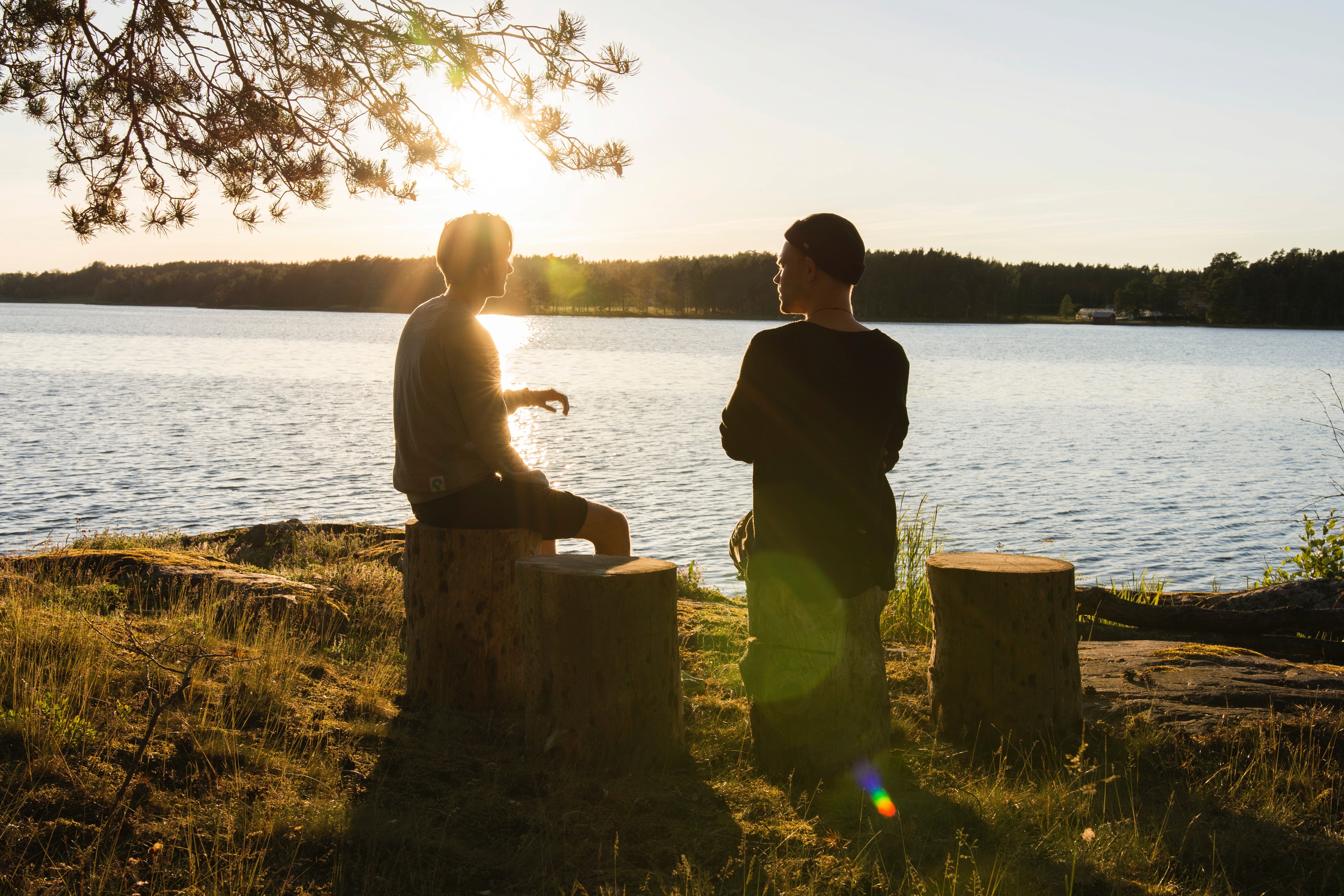 A silhouette of two friends chatting at a lake