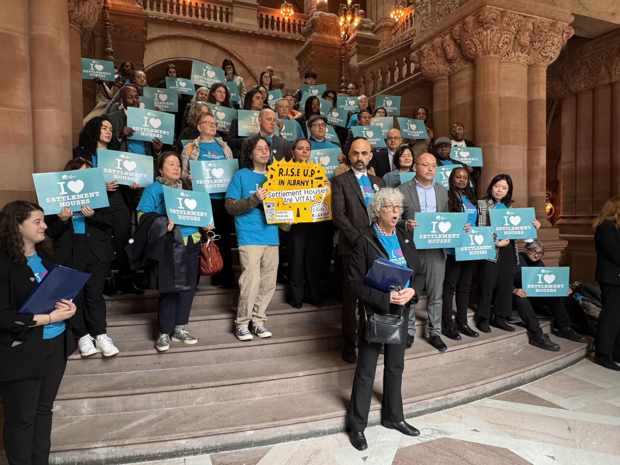 A group of advocates from United Neighborhood Houses stand on steps at the Capital building in Albany, NY.