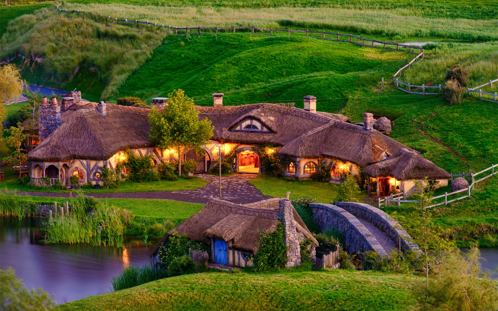 Hobbiton village with thatched cottages and stone bridge, part of Rotorua tour.