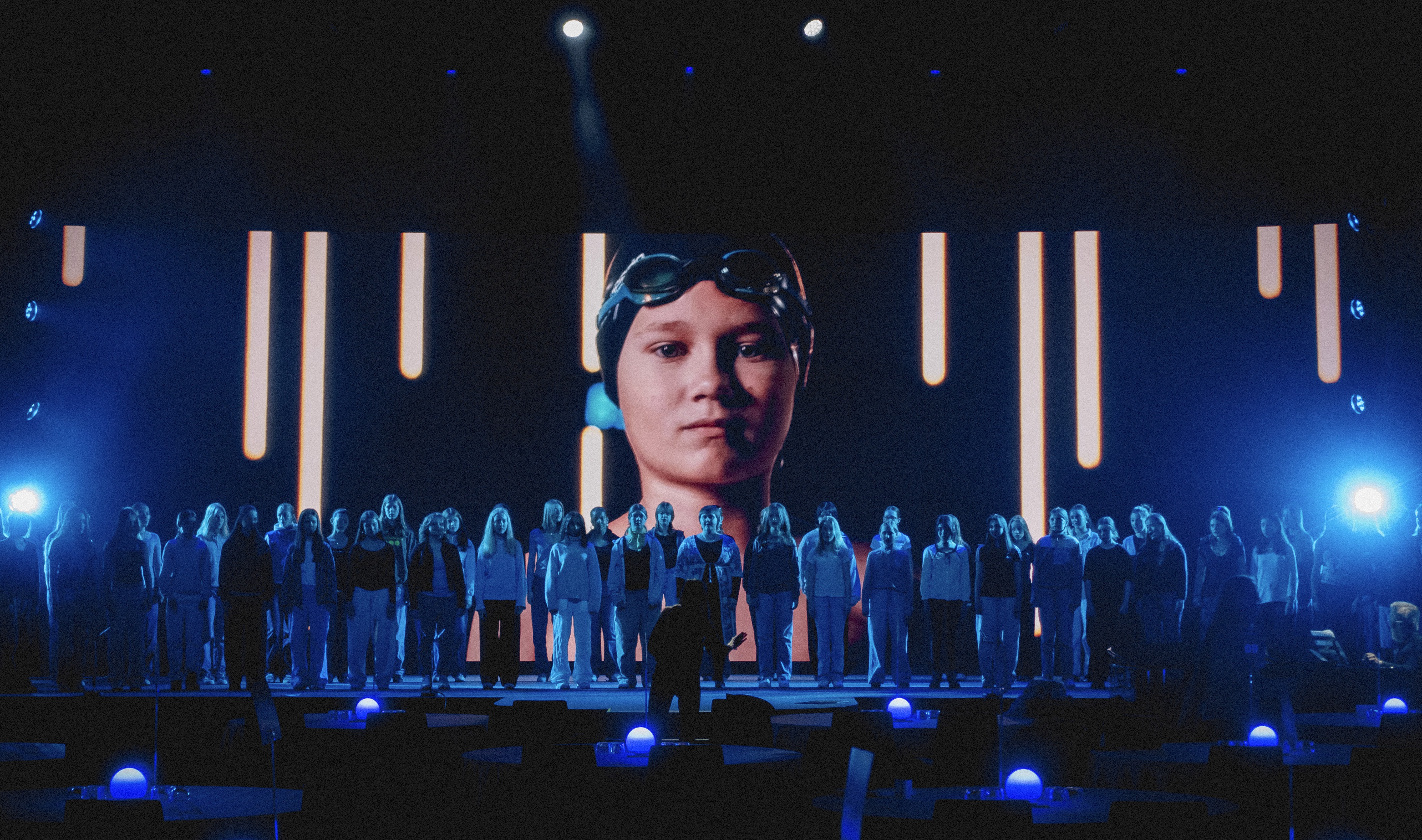 Two people standing in front of a large stage filled with people