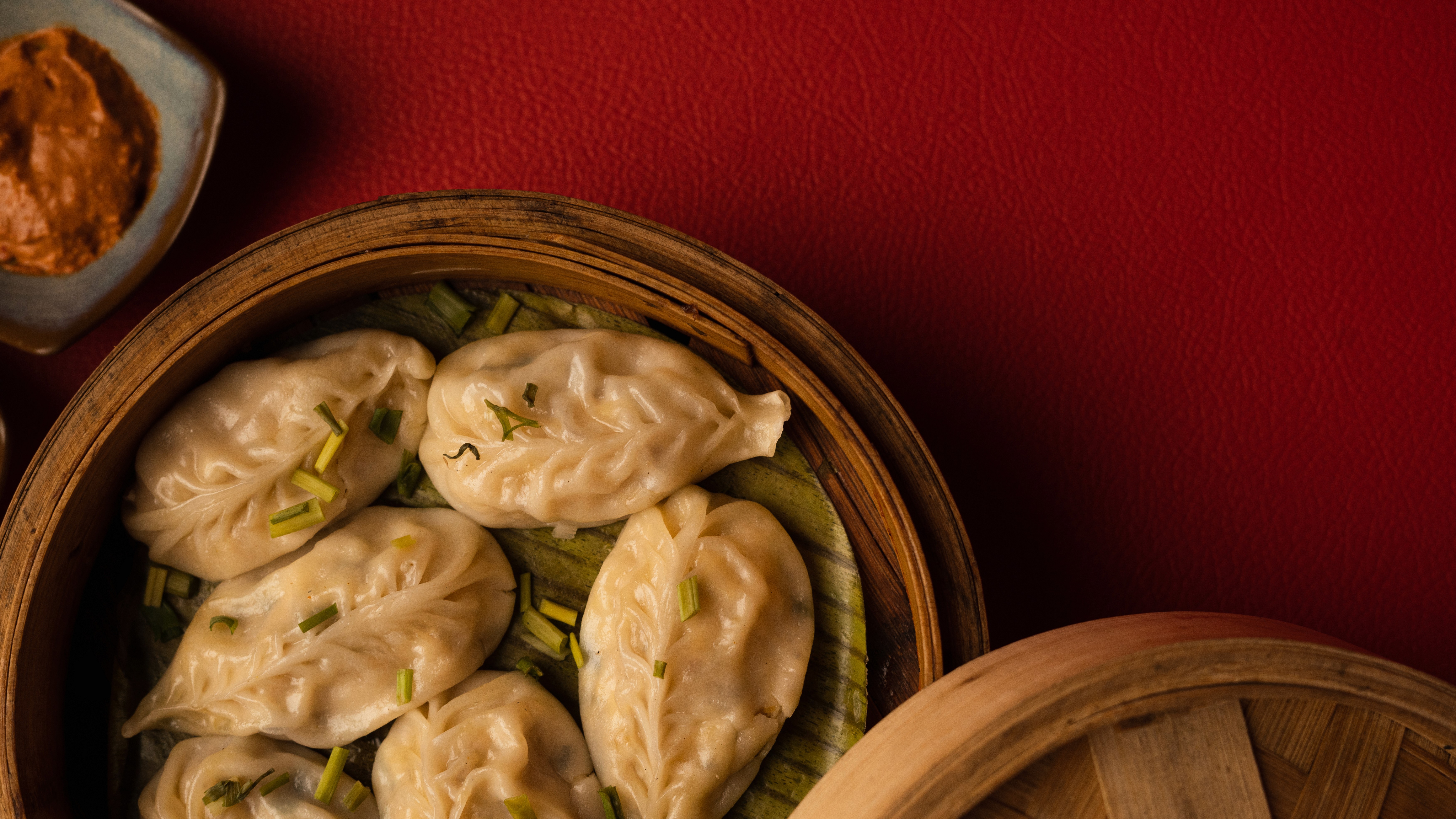 White plate with roasted chicken served in a golden sauce with herbs and capers, placed on a terrazzo tabletop in sunlight.