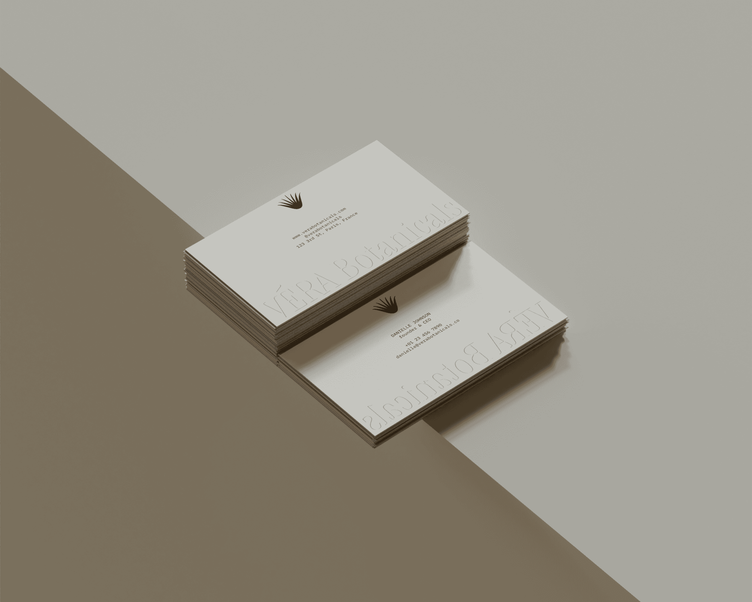 Two stacks of business cards. The cards feature the VÉRA Botanicals logo design embossed on the bottom with the company and employee details printed in the center of the cards.