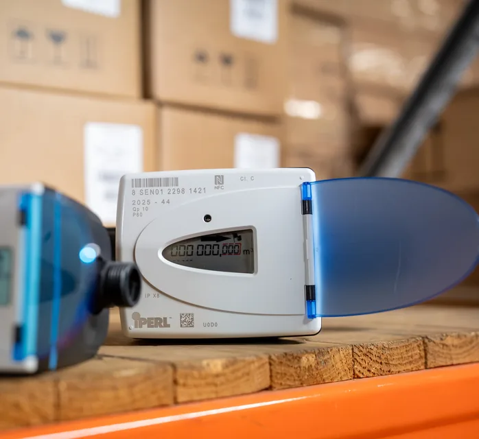 Two Sensus iPERL smart water meters on a shelf in the JOAT warehouse