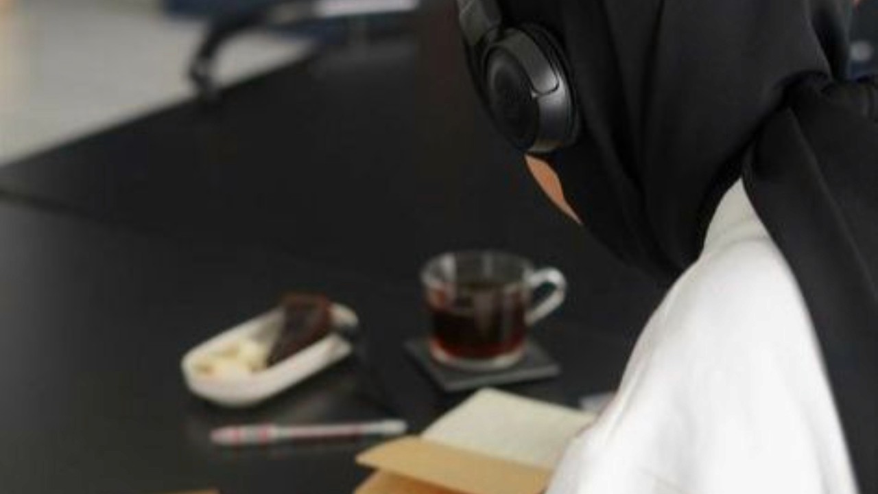 A women with a black hijab with a coffee and cake