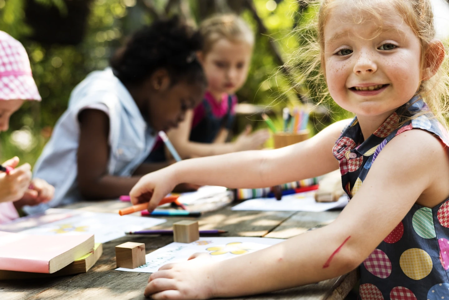 Group kids making art at a picnic table outside.