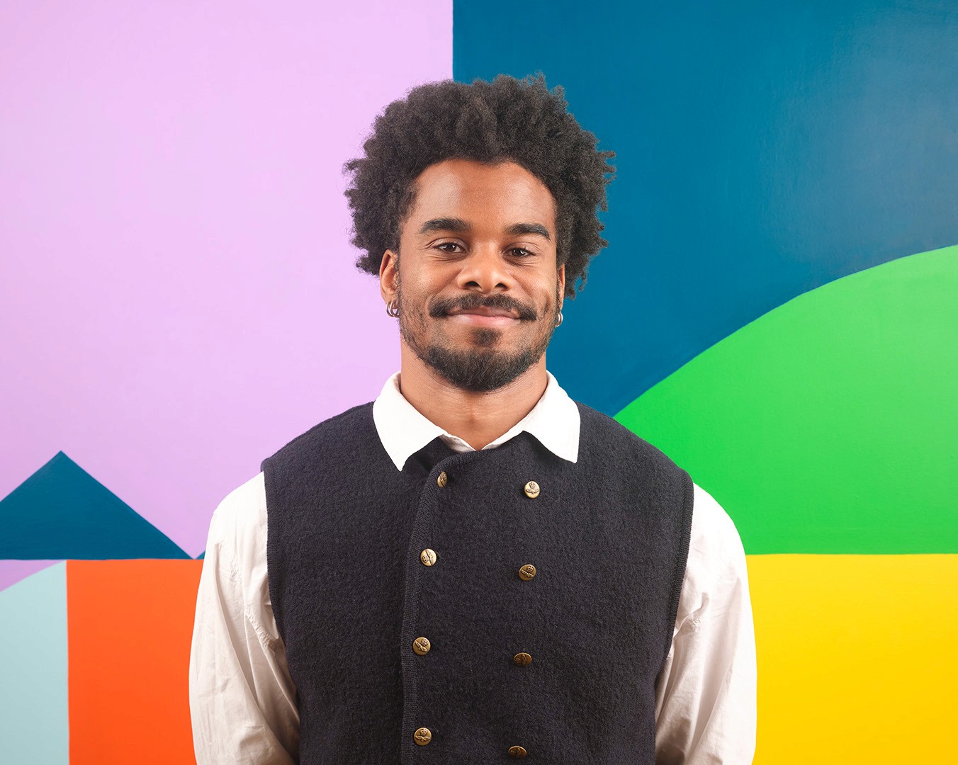 Portrait of Cianan Liburd standing in front of a colourful mural