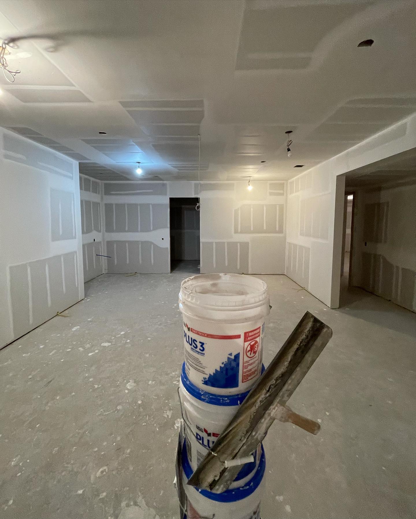 Finished drywall in an open living space, taped and ready for paint