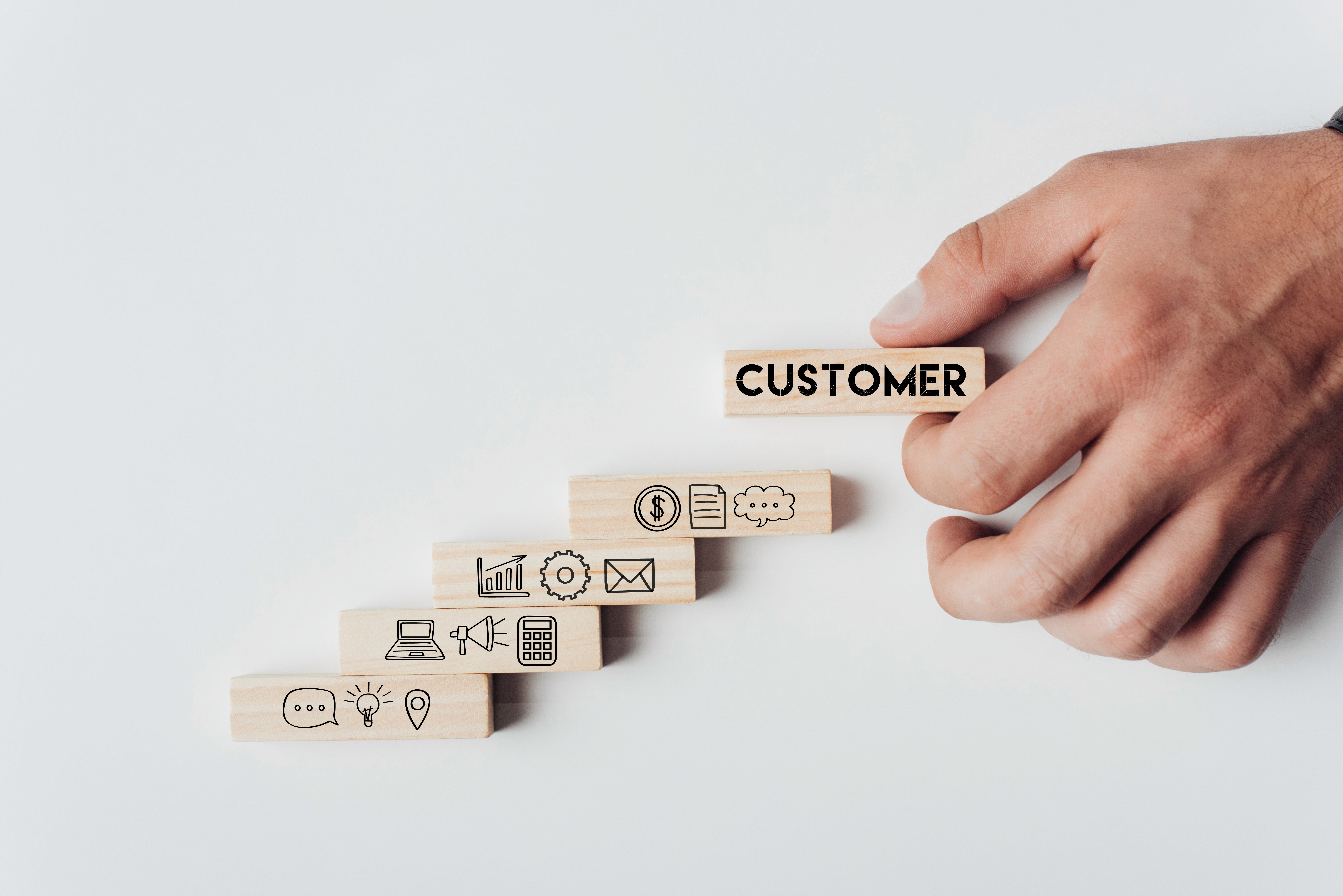 Hand placing a “customer” block at the top of a structured journey, representing aligned revenue operations, CRM integration, and marketing operations working together to drive growth.