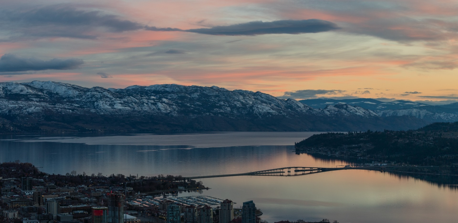 Sunset over snow-capped mountains and a Okanagan lake.