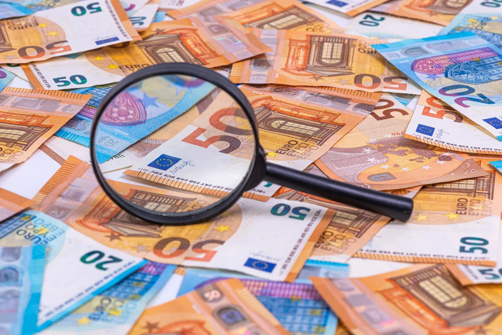 the magnifying glass lying on euro banknotes packground closeup