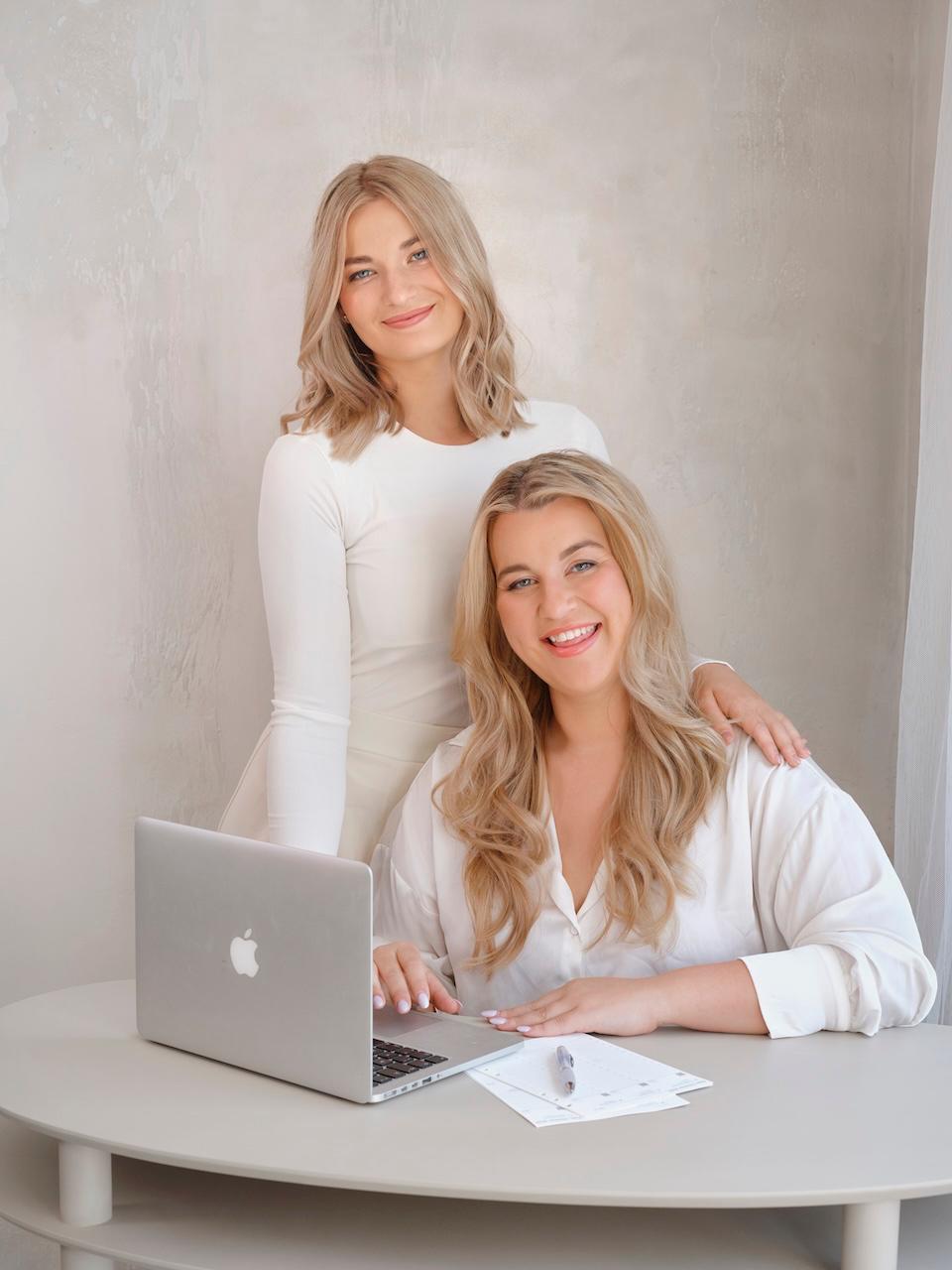 Dvě pracovnice úklidové firmy v bílém oblečení u notebooku