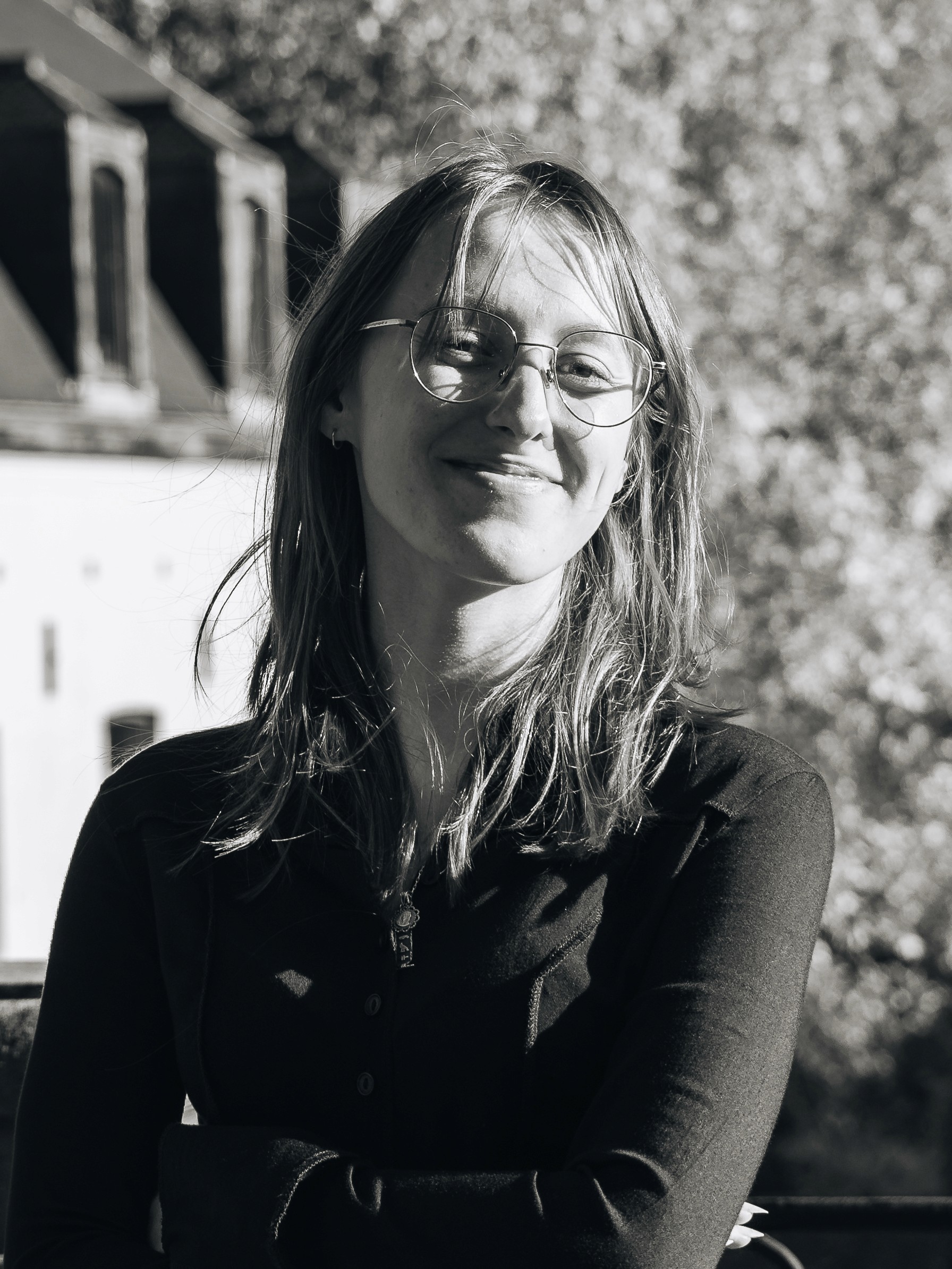 Portrait of a laughing person with curly hair wearing a white shirt