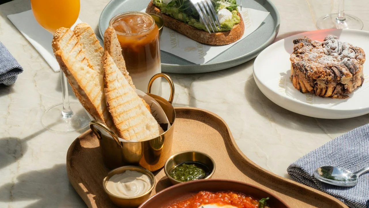 Café table with toast, pastries, coffee and a fresh juice
