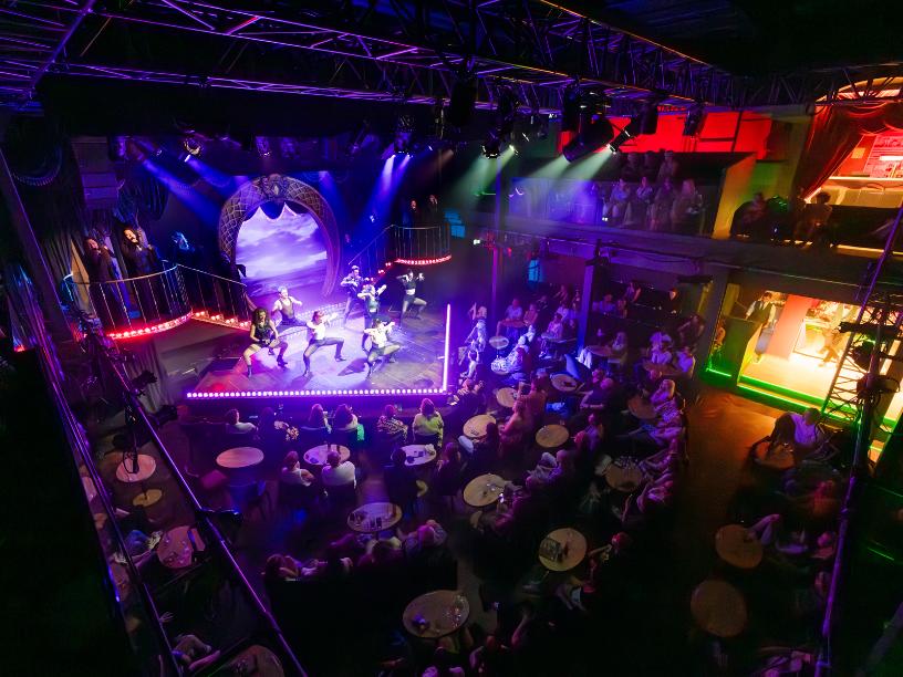 Full theatre view of the high energy Emerald Storm dance show with vibrant lighting.