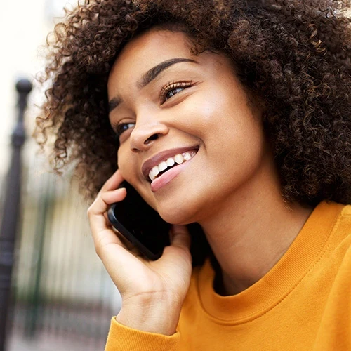 Happy african american young woman talking with cellphone in city