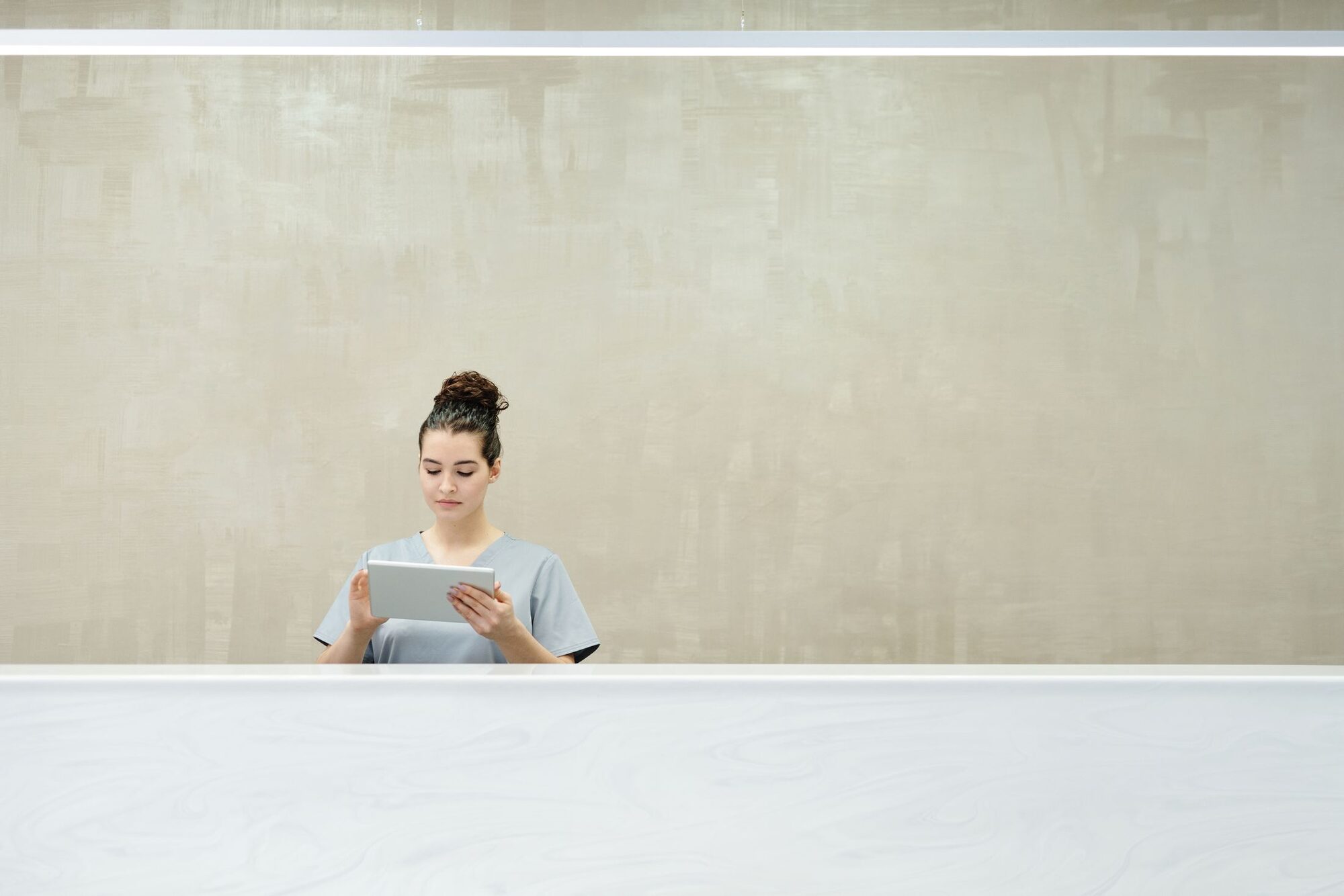 Front desk with a receptionist welcoming patients against a warm, textured beige wall