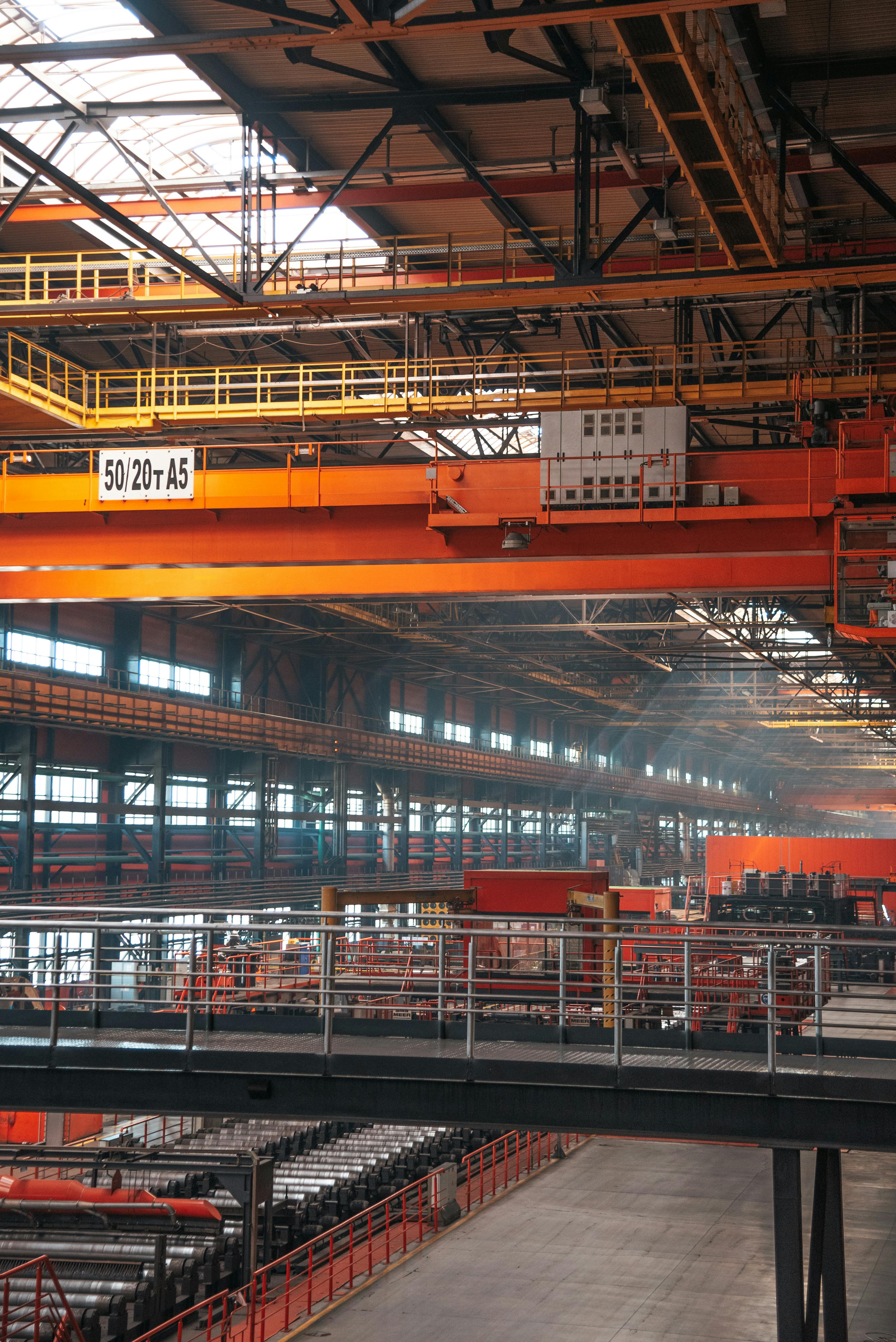 Spacious factory interior featuring large overhead cranes and metal walkways.