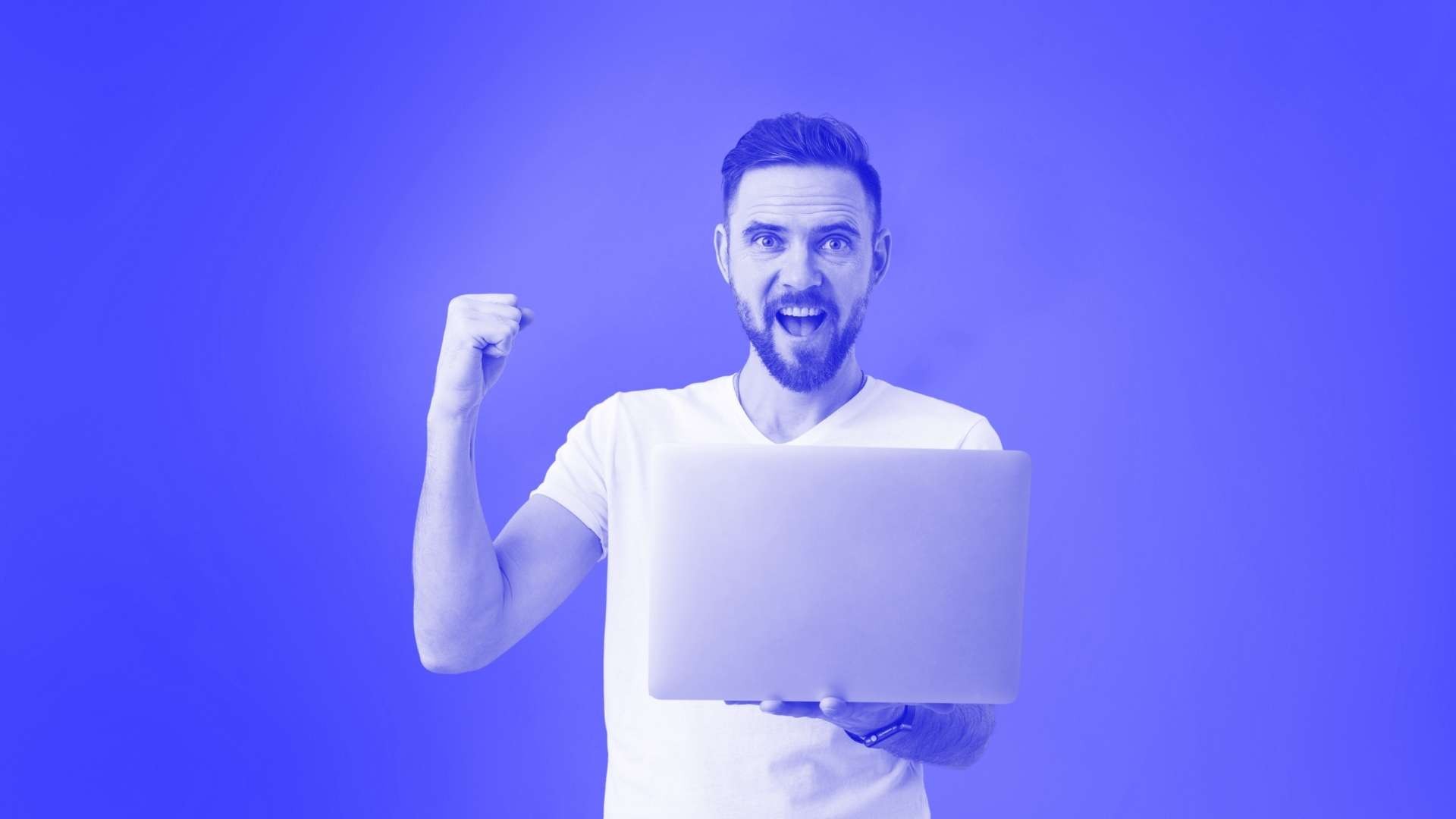 A man holding a laptop in one hand and fist bumping the air with the other