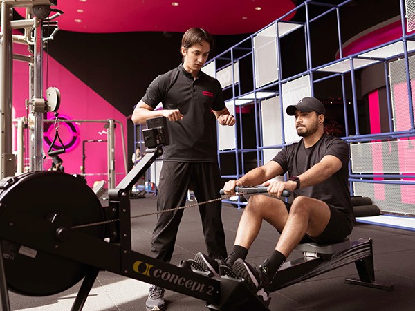 Personal Training In Kuala Lumpur, Man using a rowing machine with a personal trainiing coach