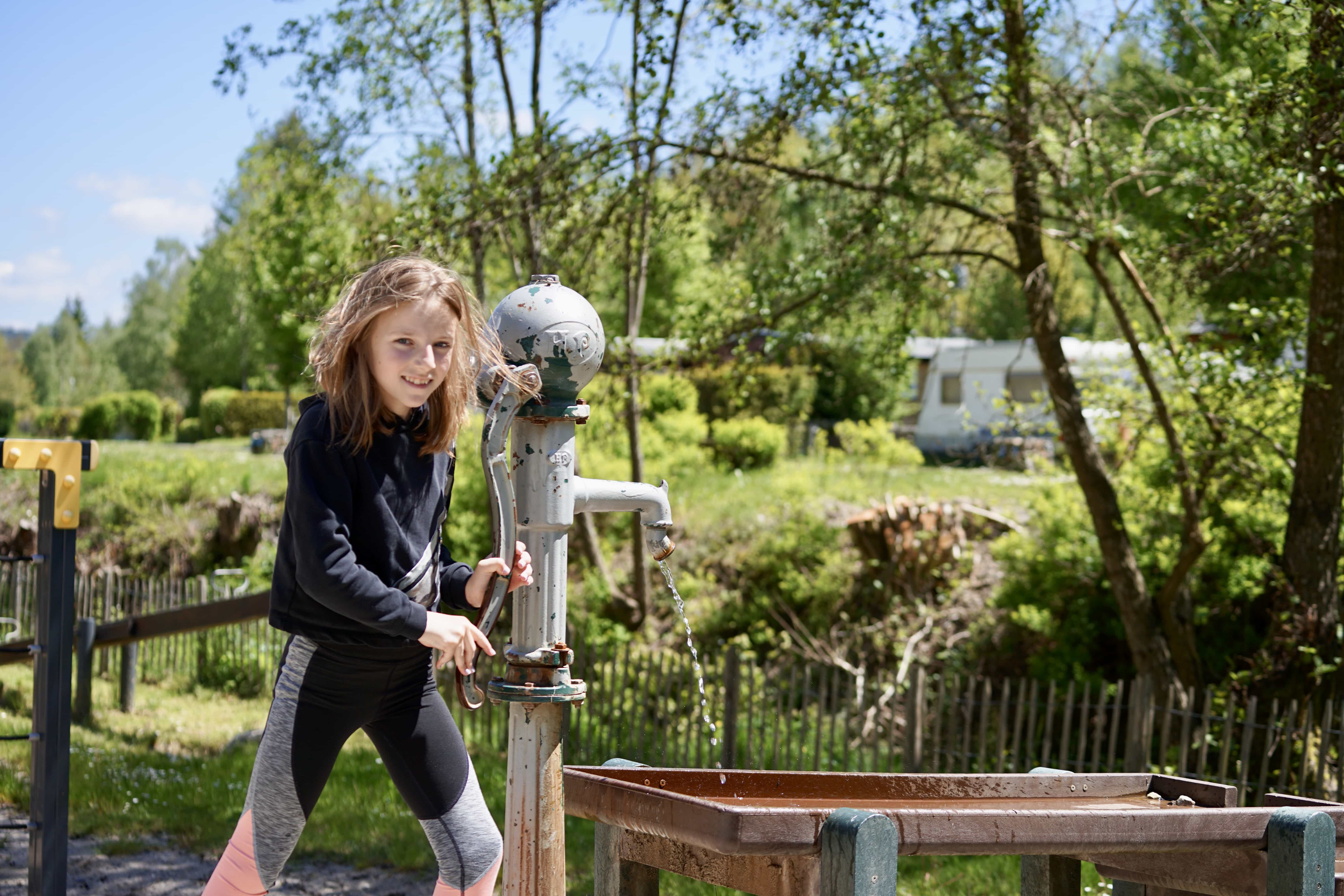 Mädchen an der Wasserpumpe
