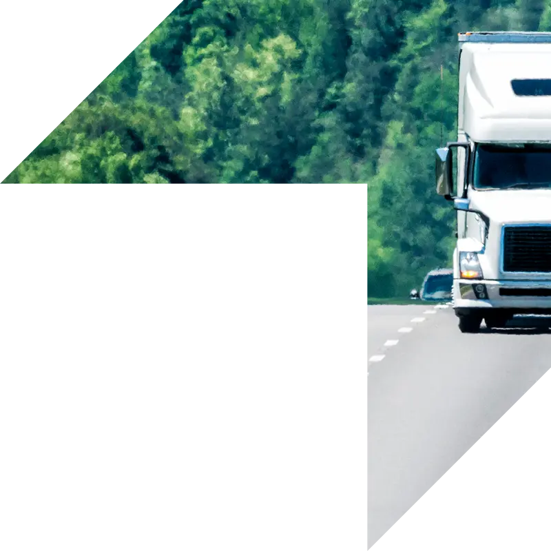 White semi-truck driving down a highway surrounded by green trees, symbolizing commercial trucking and reliable coverage.