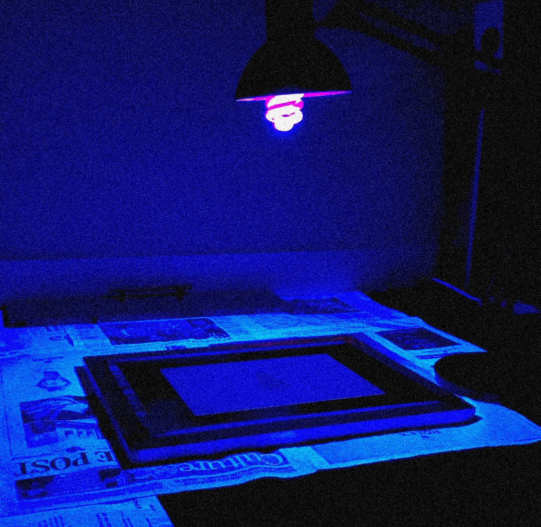 screen printing dark room set up, blue light and old newspaper underneath.