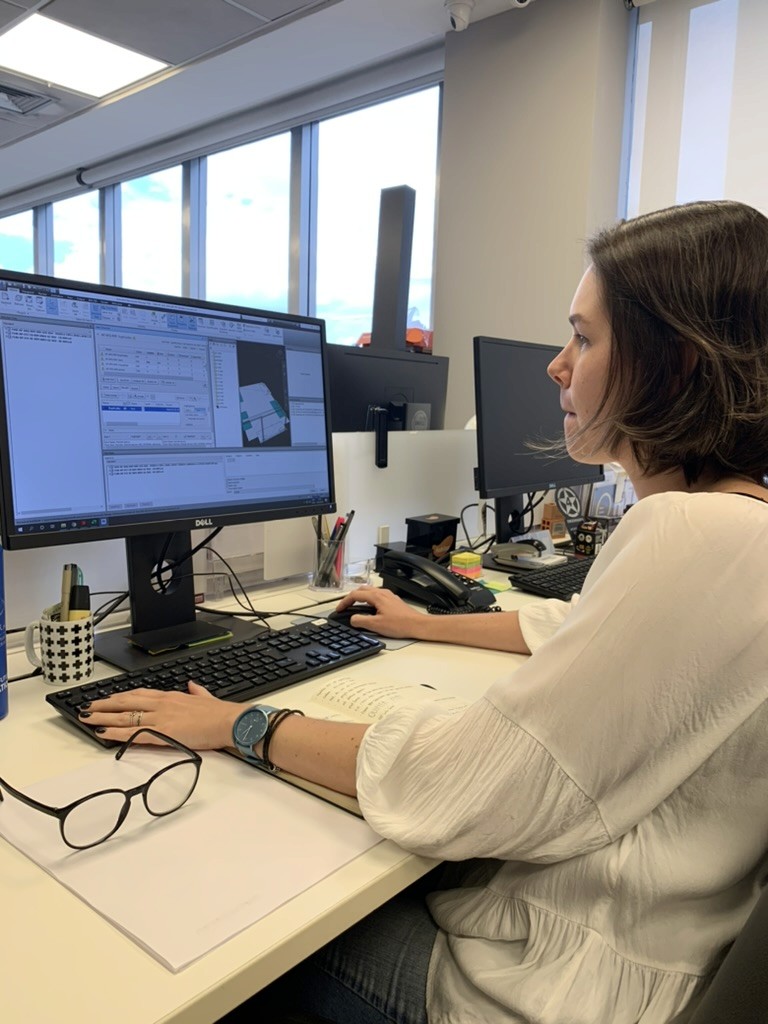 Woman sitting at a desk using a software with a 3D model of a building project