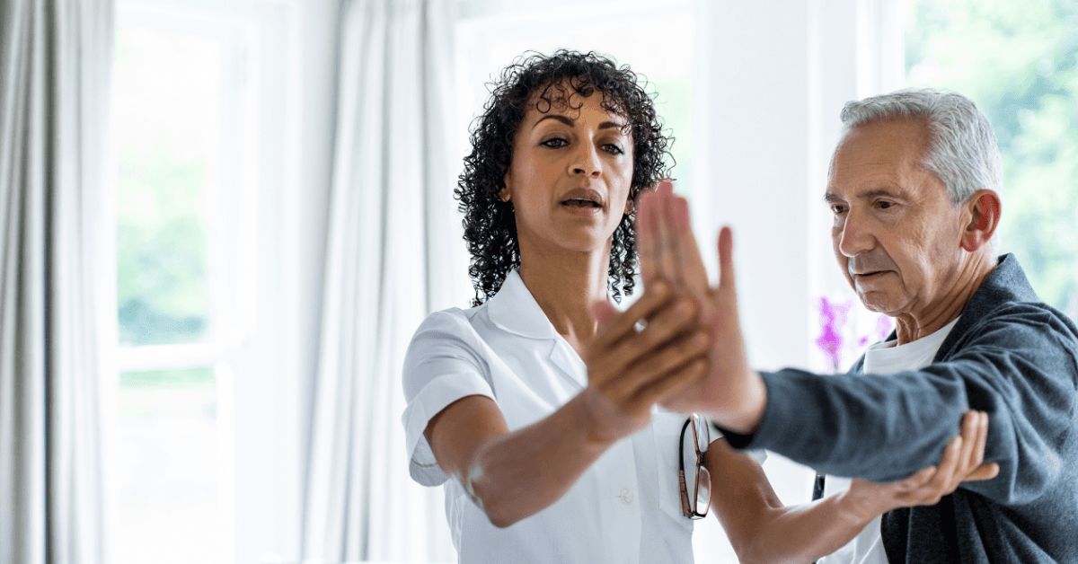 A concierge therapist works one on one with an elderly client in their living room.