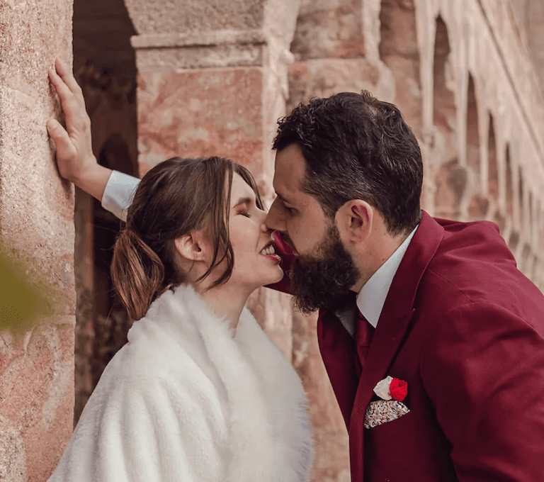 Couple de marié qui s'embrasse sous une voute de pierre