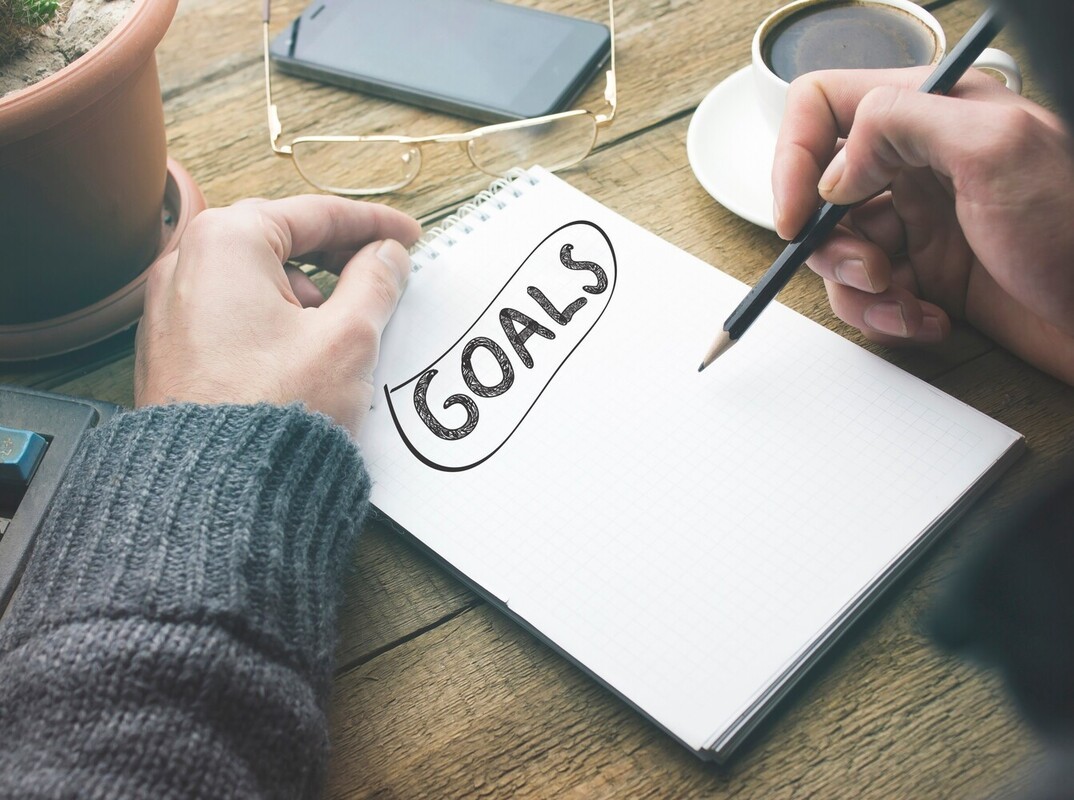 closeup of a person writing their exercise for beginners to lose weight goals in a notebook