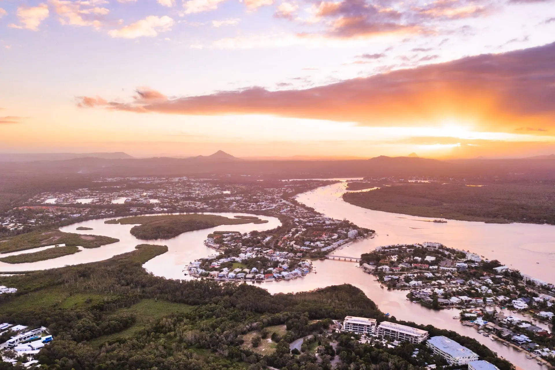 Aerial view of a winding river and coastal town at sunset.