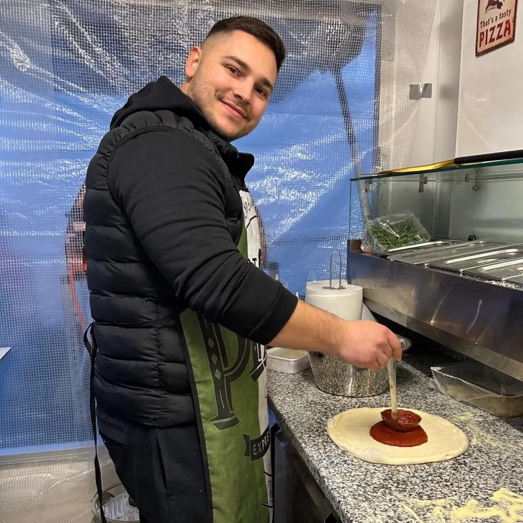 Pizzaiolo verteilt Tomatensauce auf frischem Pizzateig in Foodtruck Pizza Dielsdorf