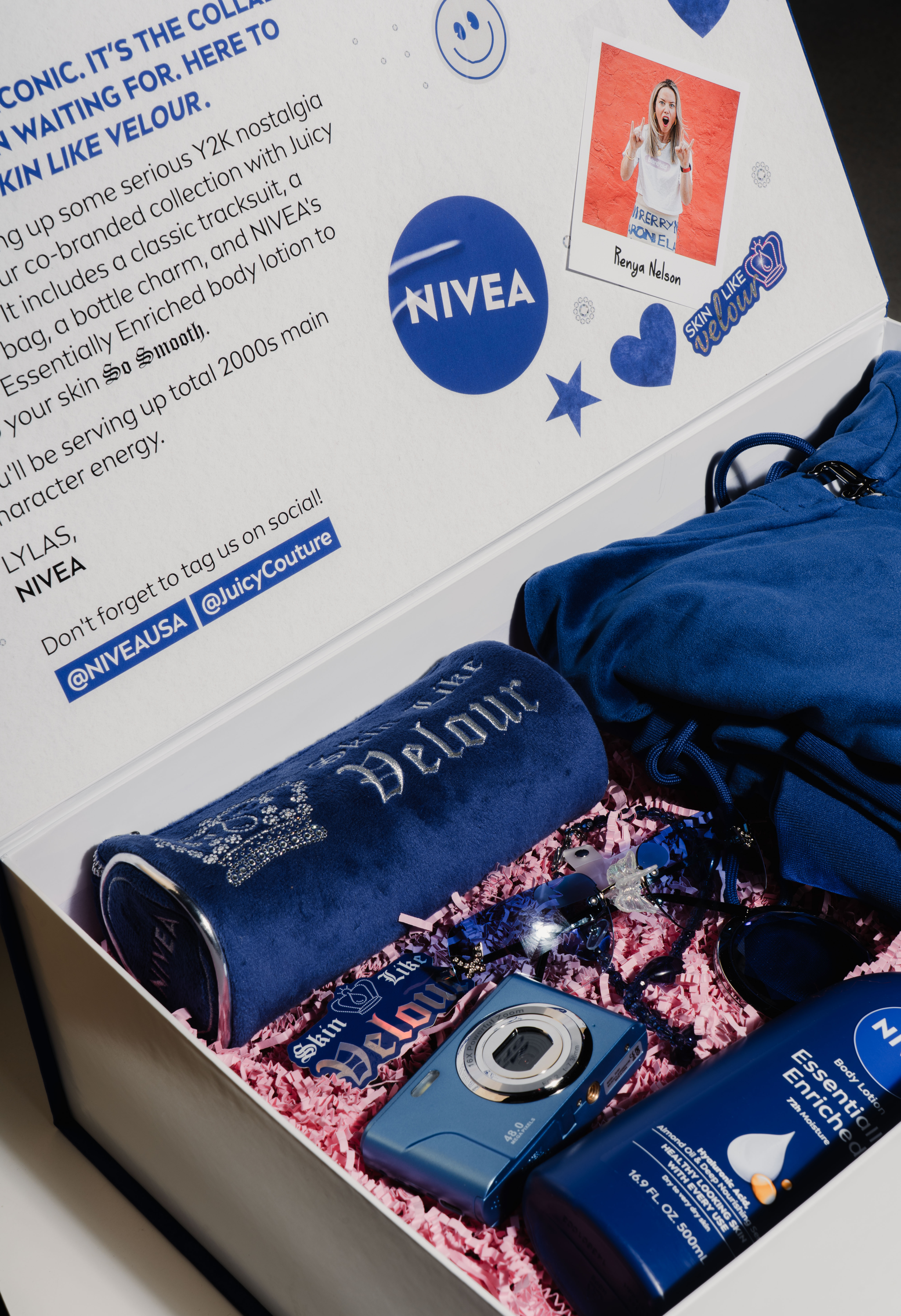 A box that is open that has text on the inner lid talking about this specific nivea campaign that has a fake poloroid of the respective influencer. The inside of the box holds 2 juicy couture velour items, a digitial camera, lotion from nivea, sunglasses, stickers, and a phone charm