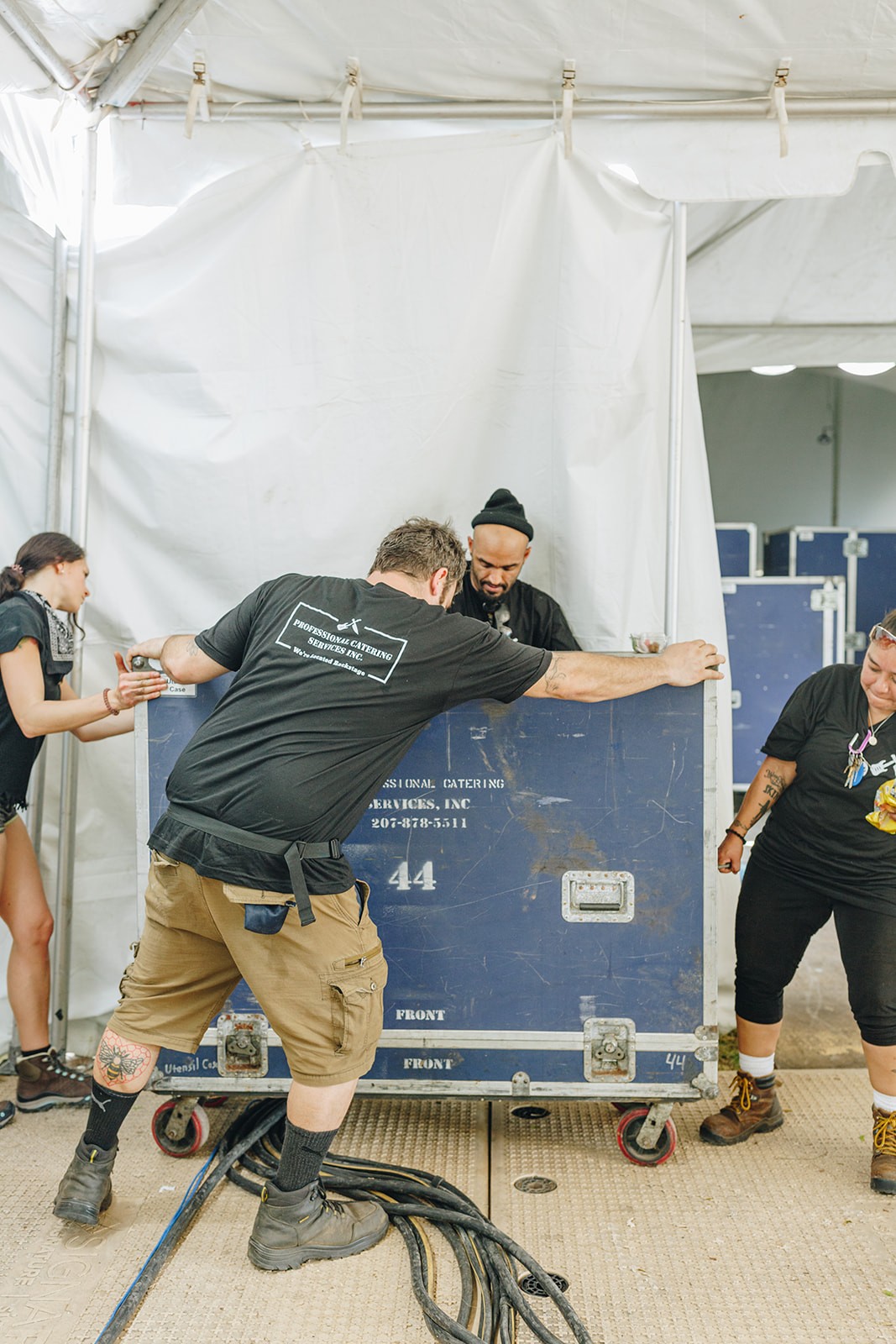 A group of people are working together inside a tent, setting up or managing equipment.