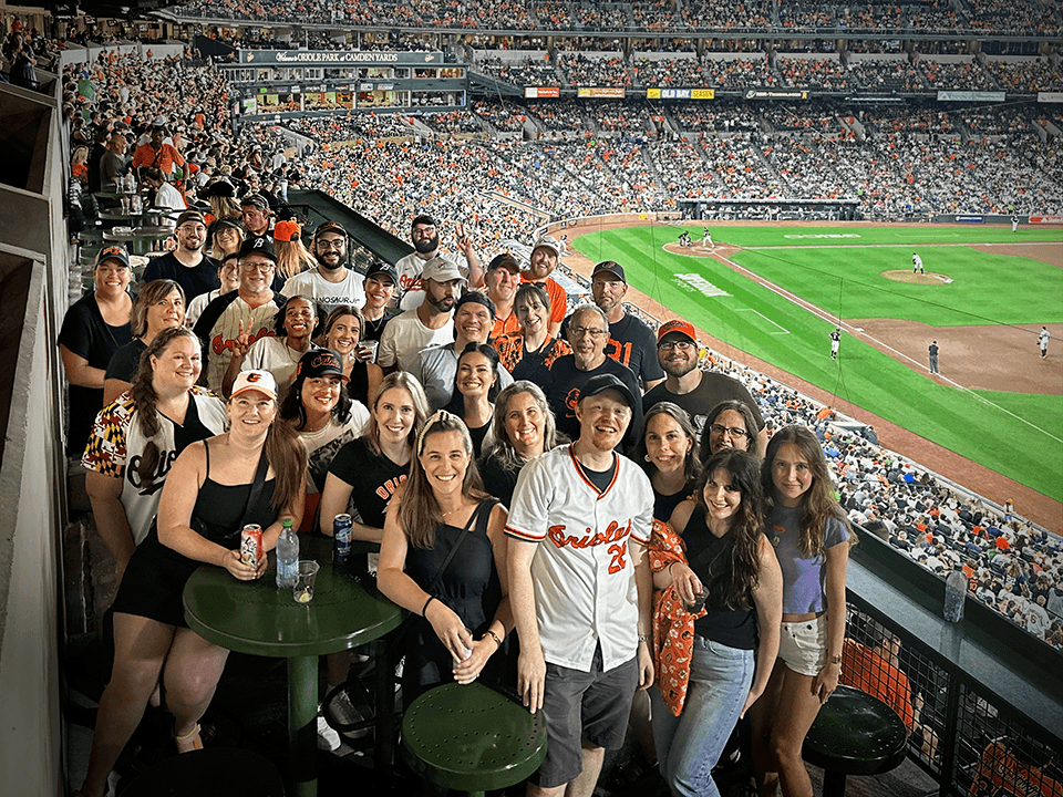 A woman with red hair smiles while holding a small potted succulent outdoors in front of a brick building, reflecting how you can grow your career in an inspiring agency environment.