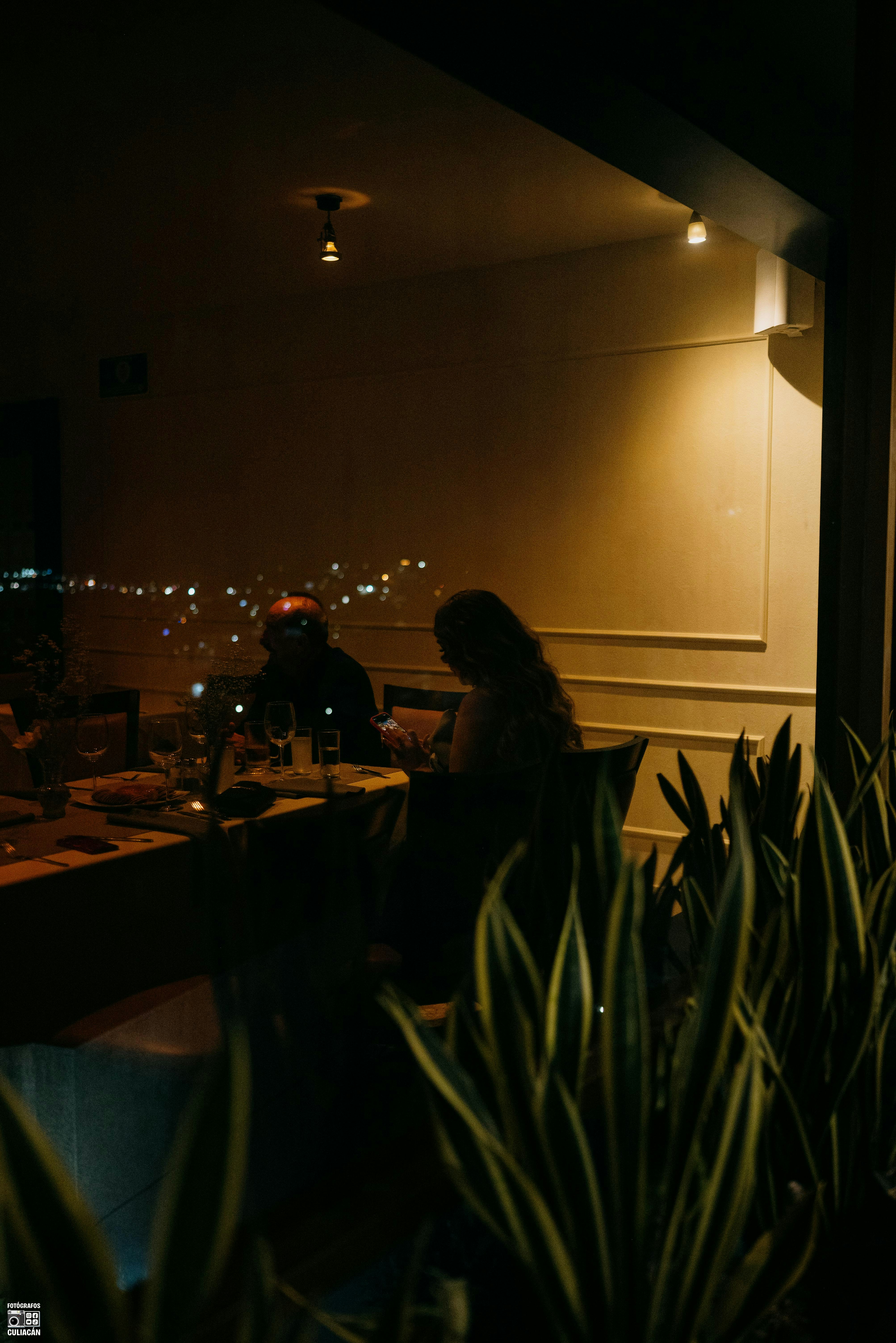 People dining at a restaurant seen through plants.