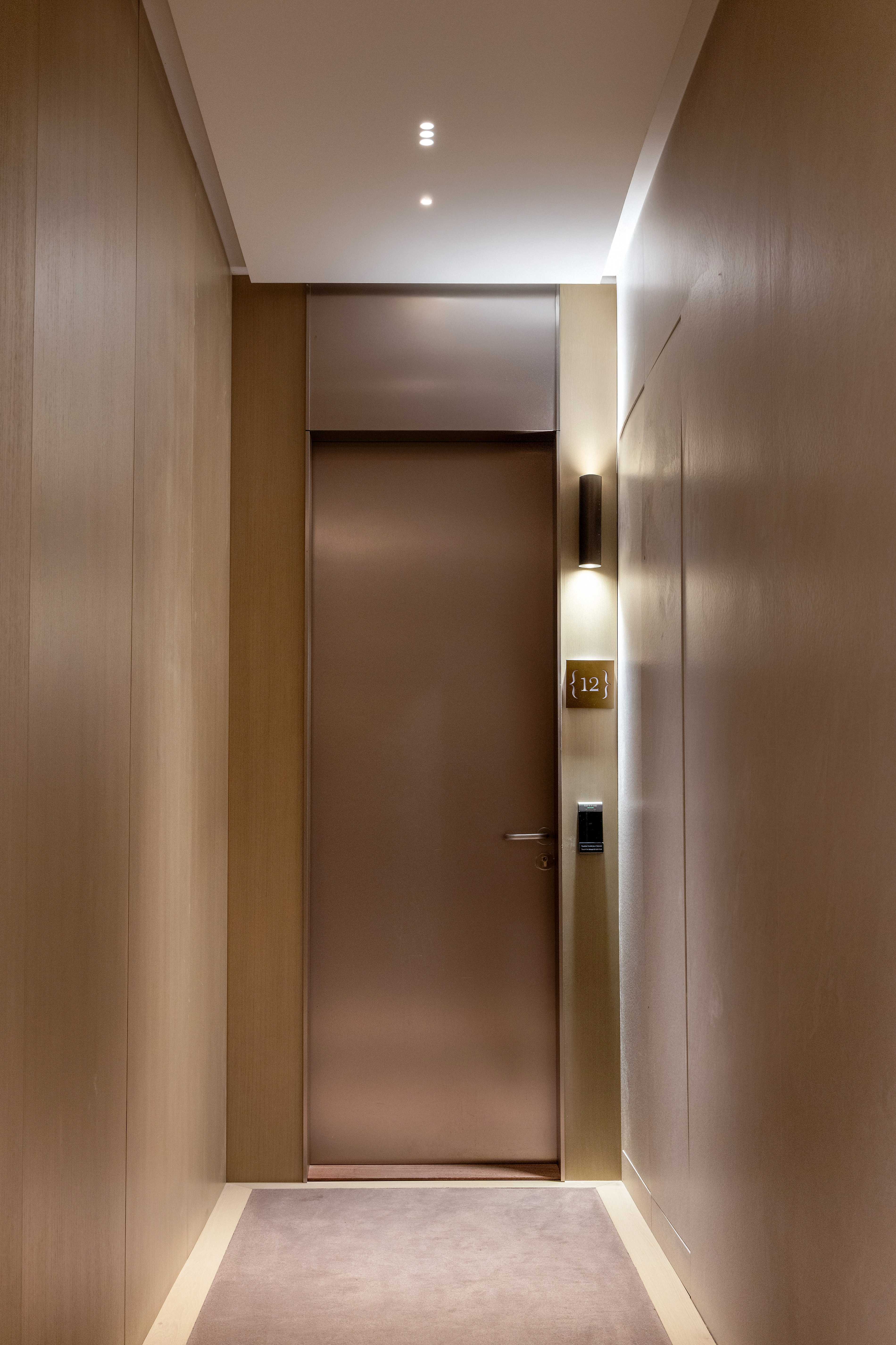 Porte d'entrée de la suite numéro 12 en fin de couloir avec éclairage tamisé et boiseries