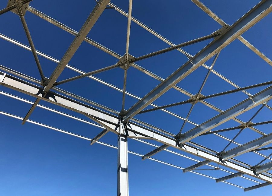 Charpente métallique en treillis, photographiée en contre-plongée contre un ciel clair.