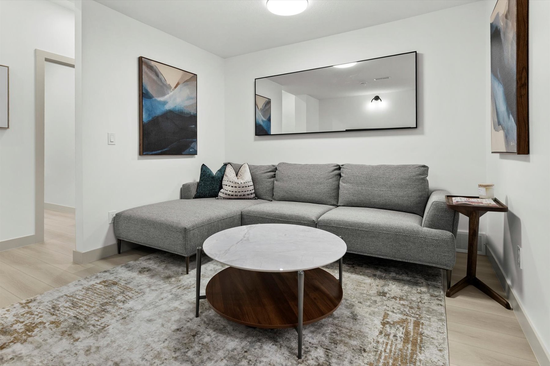 Legal suite living room after: grey sectional, round coffee table and framed artwork